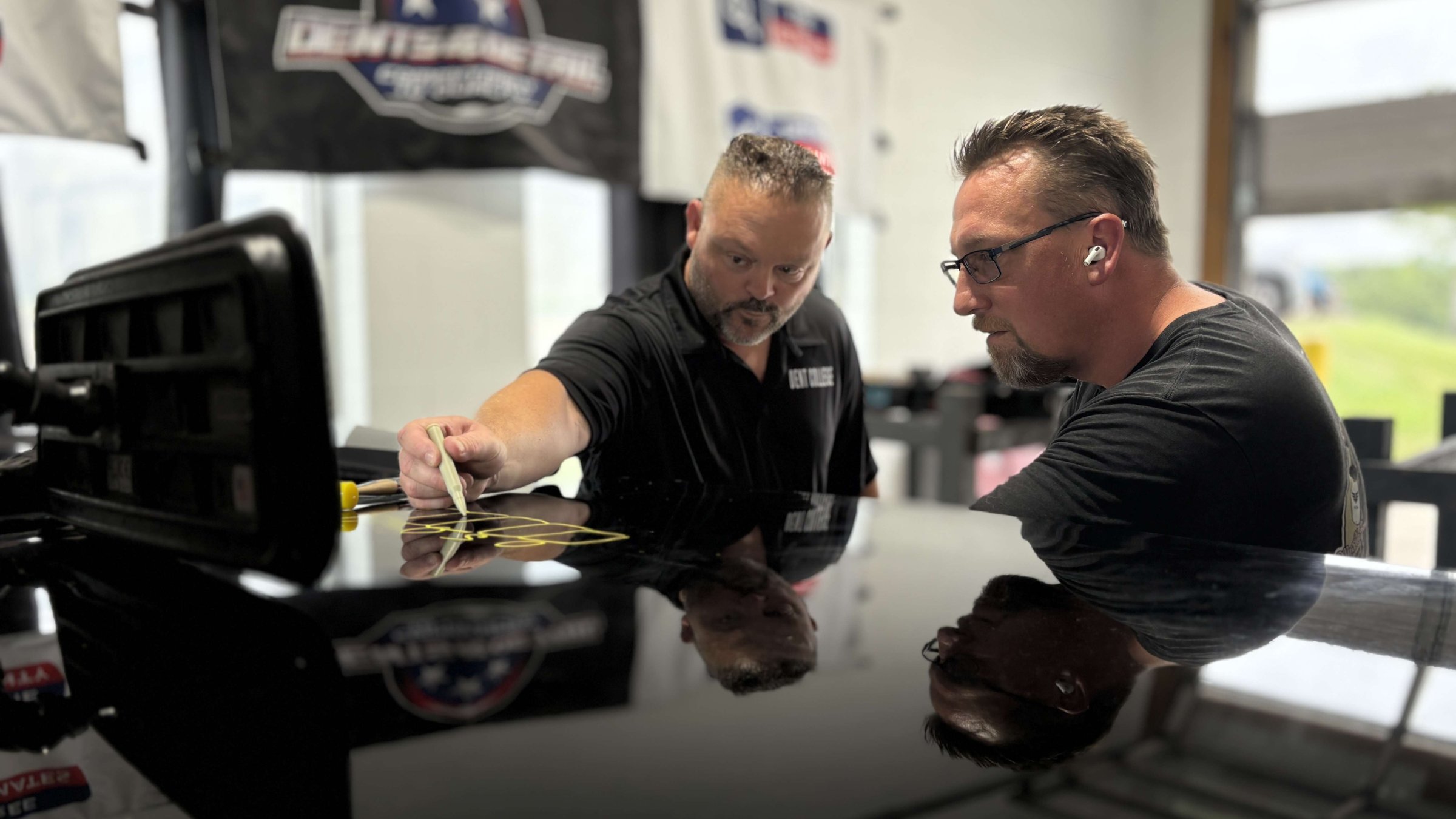 PDR instructor demonstrating dent assessment technique on a vehicle panel at Dent College in Knoxville, TN